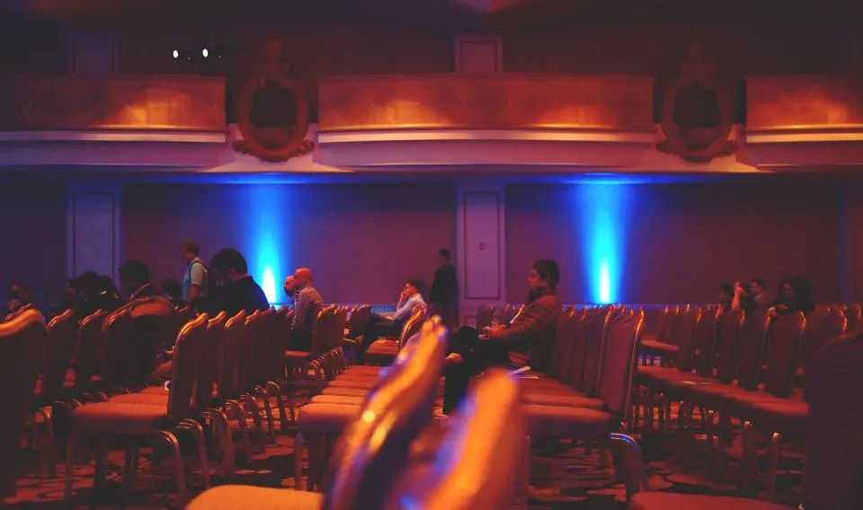 Audience seated in an event hall before a stage